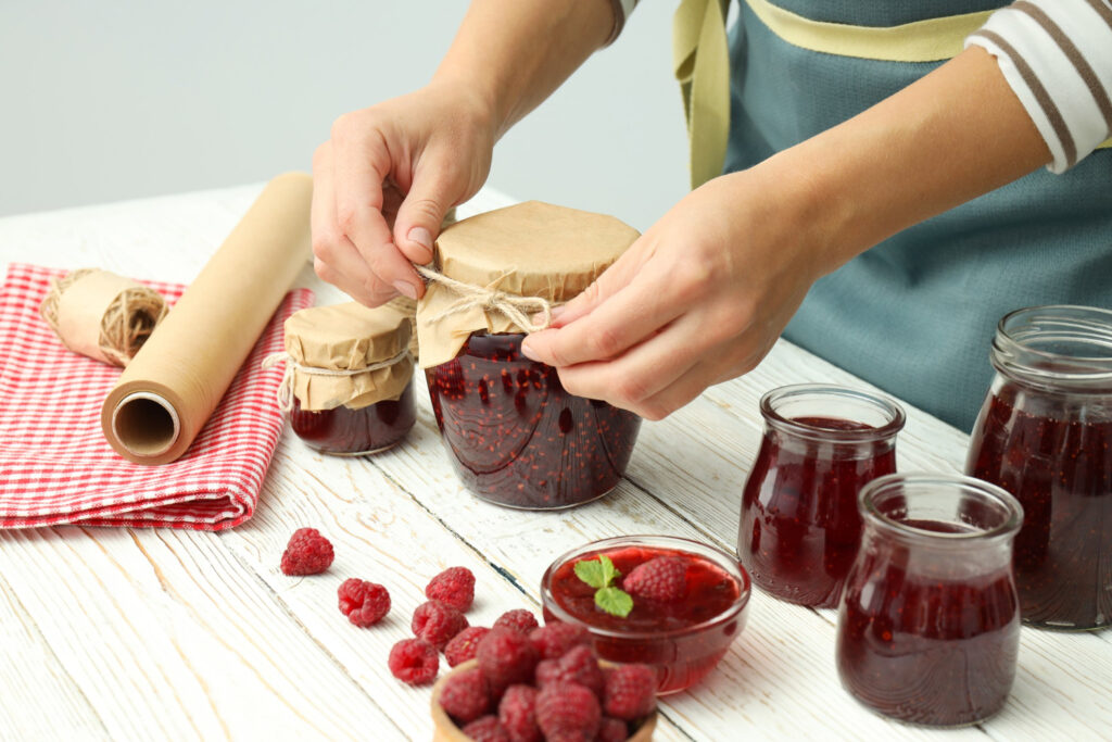 concept of cooking raspberry jam on white wooden table.