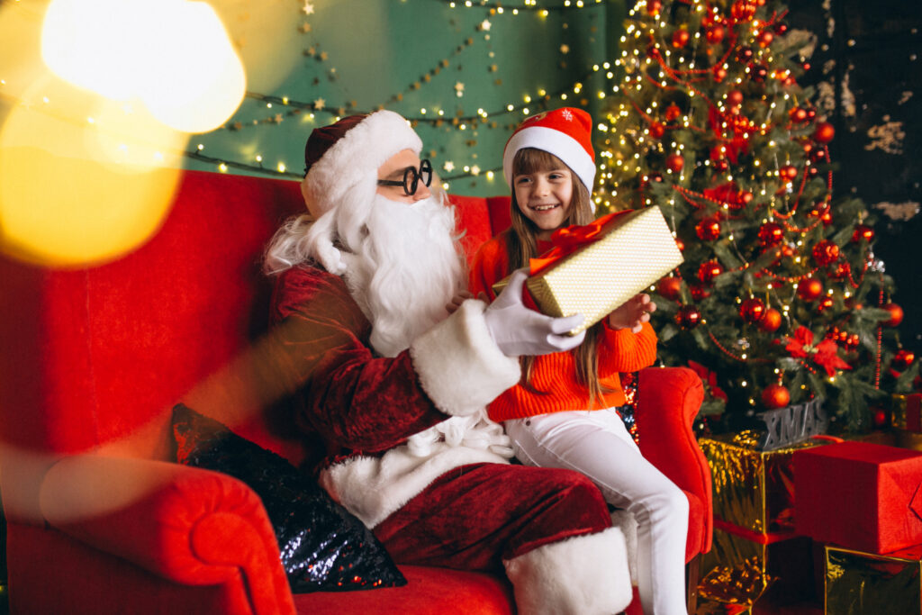 little girl sitting with santa and presents on christmas