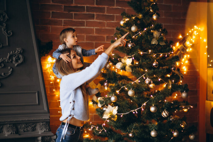 mother with little daughter decorating christmas tree