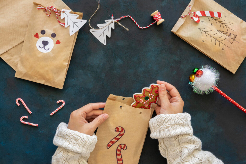 top view of hands putting treats inside christmas gift bags