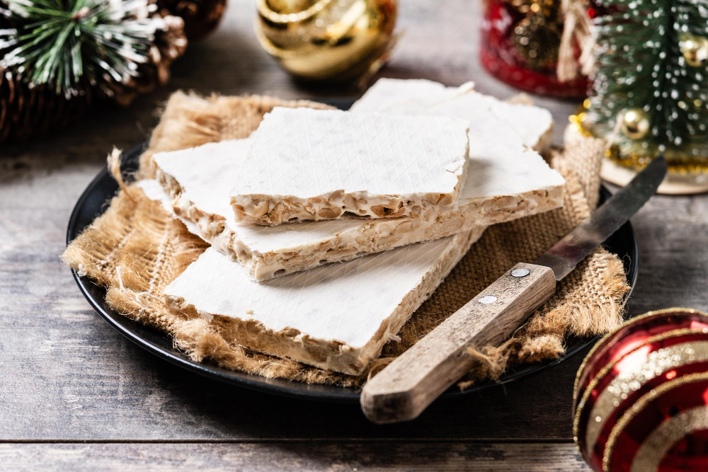 traditional christmas sweet nougat and christmas sweet almonds on wooden table