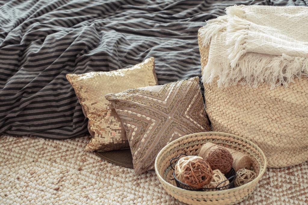 wicker straw large bag, pillows and decorative elements on background of the bed.