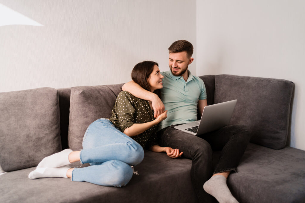 man and woman sitting on sofa with a laptop