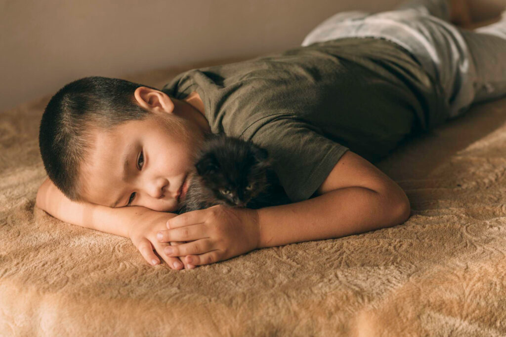 asian boy lying on the floor with a kitten