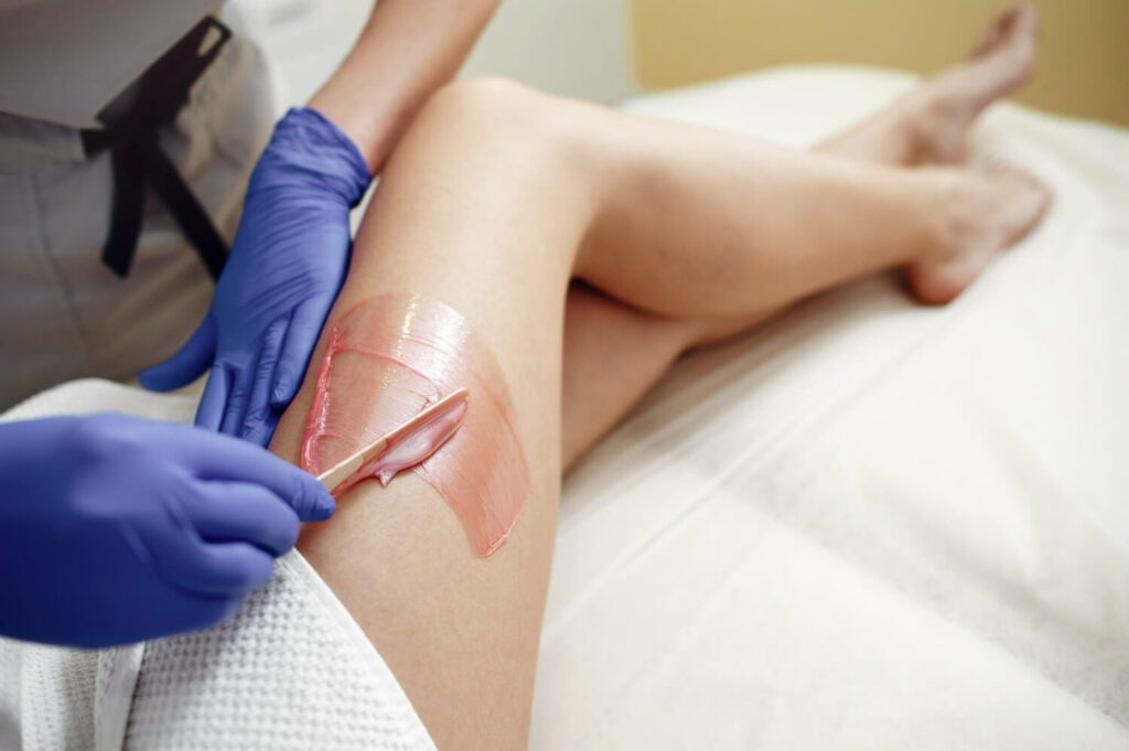 a professional waxing the legs of a woman