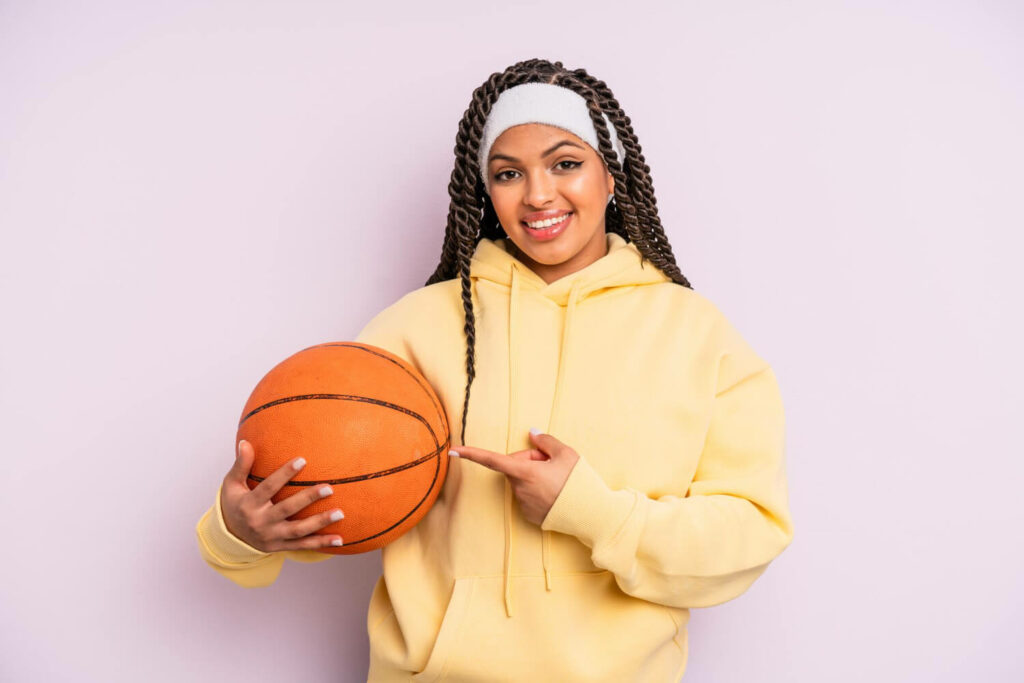 a girl holding a basketball ball and wearing a headband